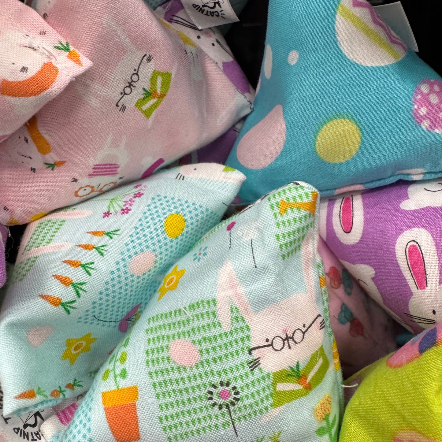 A collection of Easter-themed Happy Sack catnip toys featuring bunnies, Easter eggs, pastel colors, and springtime patterns, perfect for playful cats made by CatnipTakeout