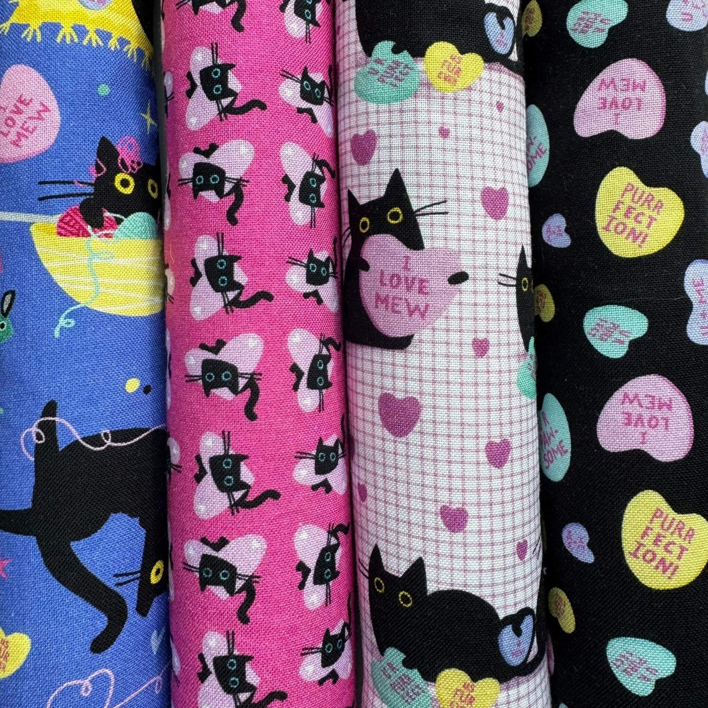 A collection of four Valentineās-themed fabric patterns featuring black cats with whimsical designs, including hearts, wings, conversation hearts, and playful elements, used for catnip cat toys made by CatnipTakeout.
