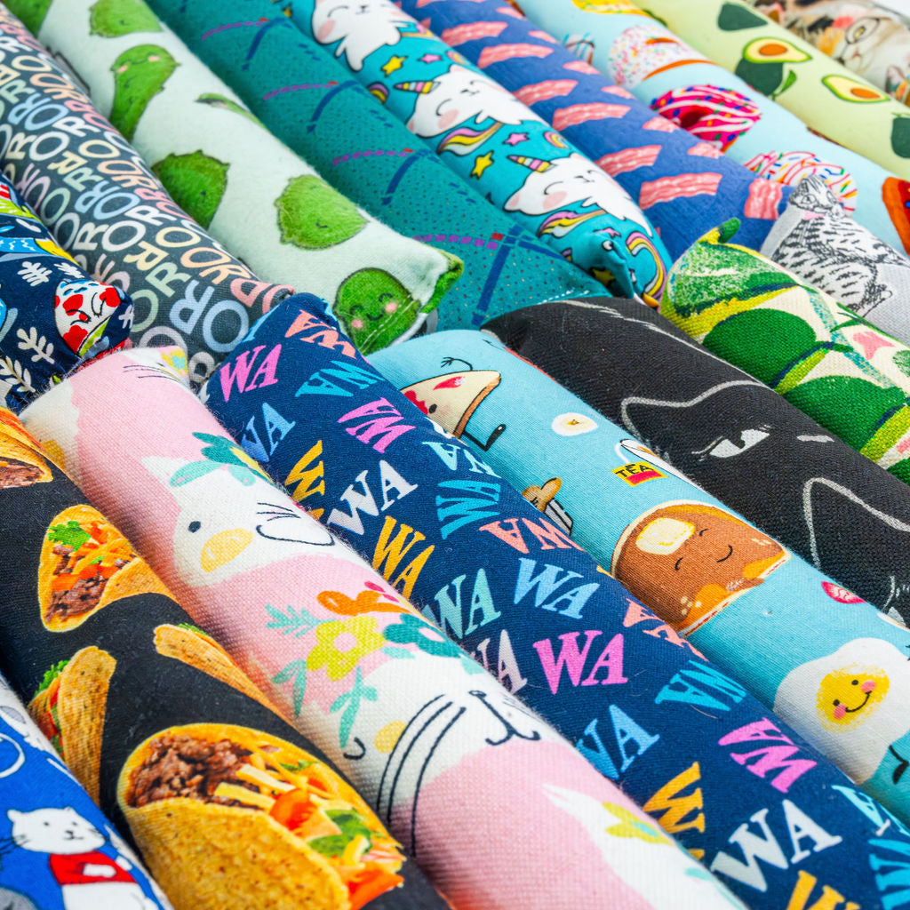 A colorful assortment of kicker shaped catnip toys featuring vibrant designs, including food prints, rainbow patterns, and playful animal themes.