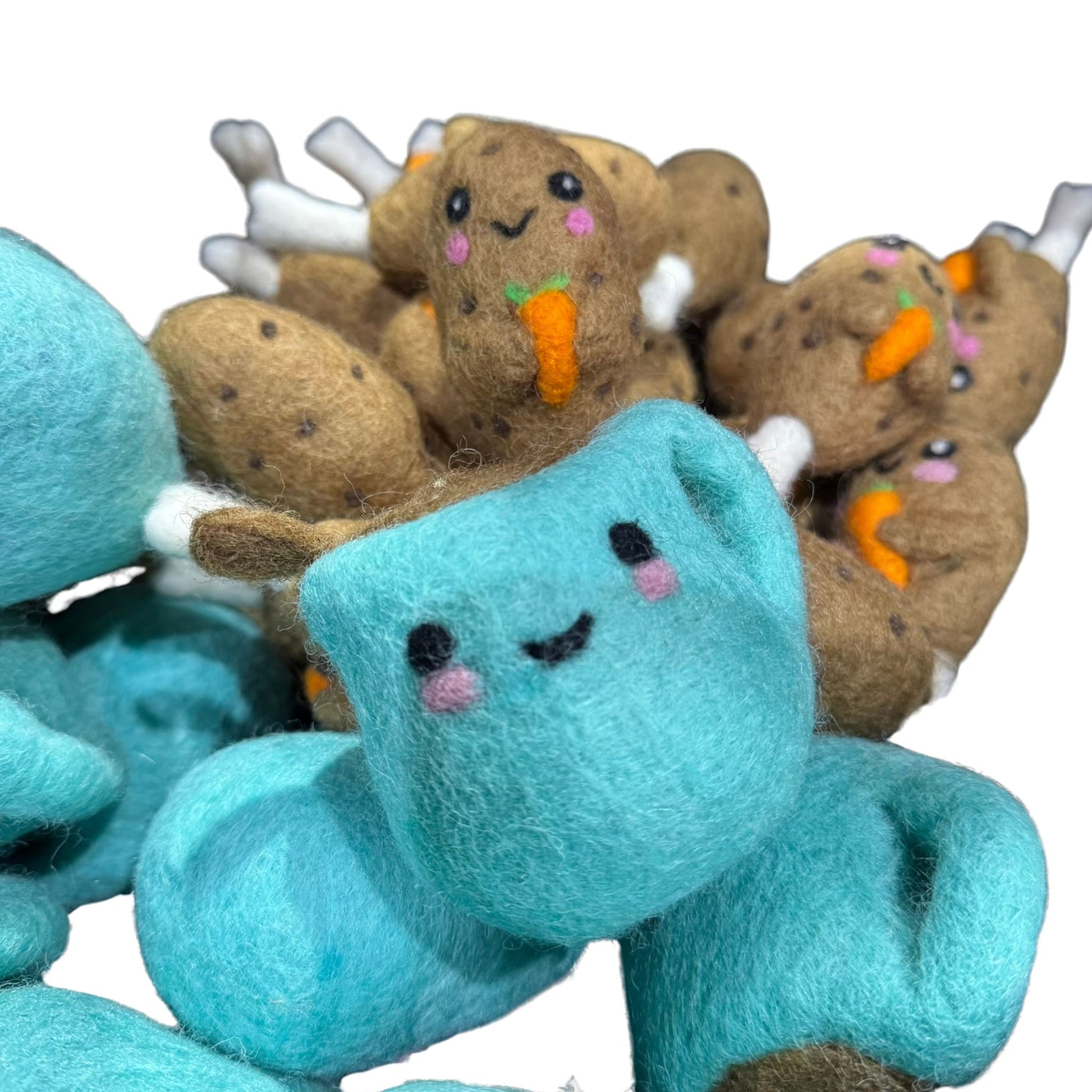 A group of hand-felted wool turkey cat toys with carrot details paired with cute blue mug wool toys, all crafted from organic wool and finished with CatnipTakeout catnip spray.