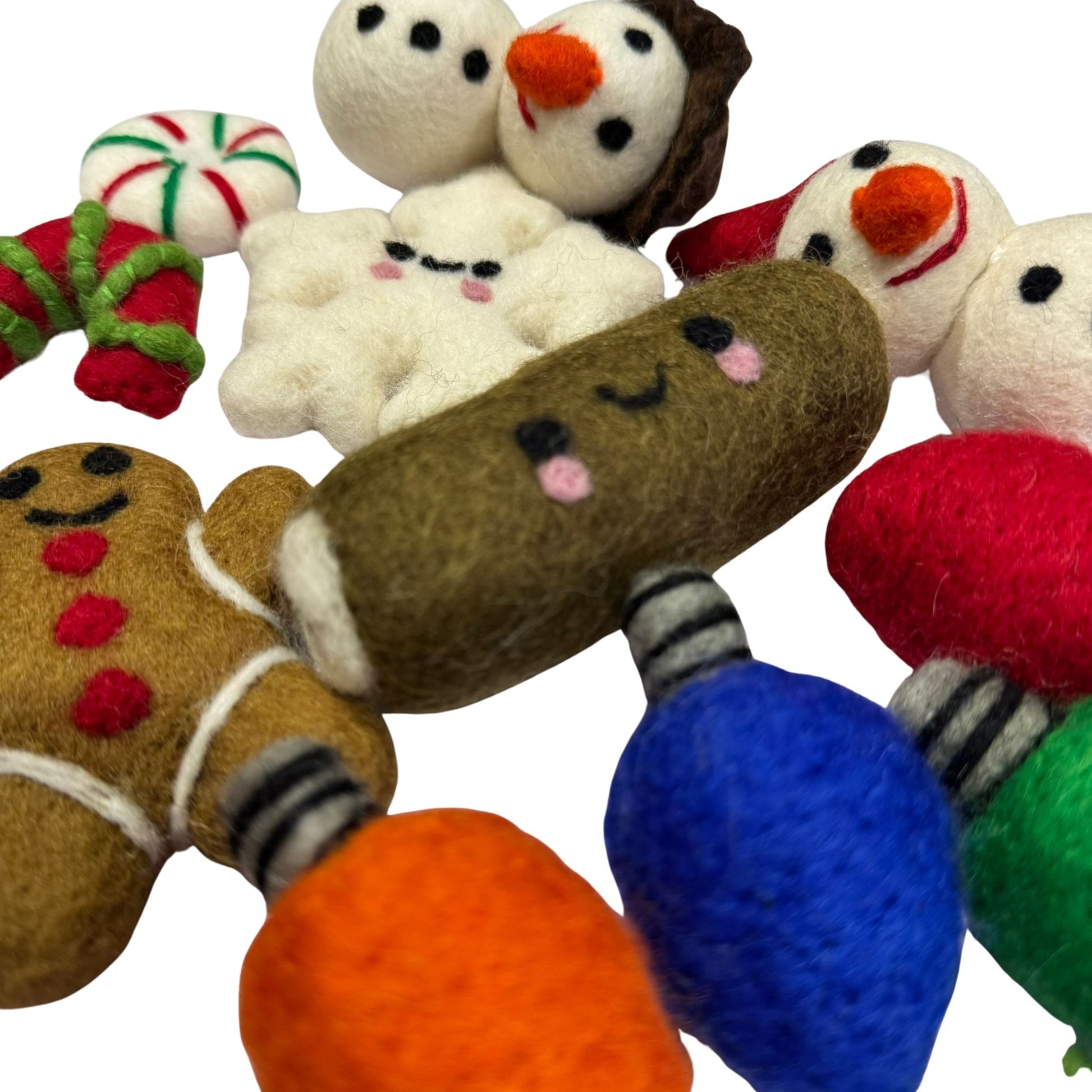 Hand-felted gingerbread cat toys surrounded by smiling wool snowman toys, crafted from organic wool and finished with CatnipTakeout’s signature catnip spray. 