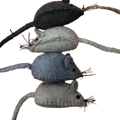 Three gray felted mouse toys stacked on a branch against a white background