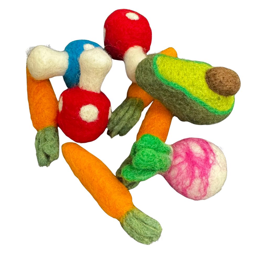 Angled view of the veggie cat toy collection including carrots, red polka-dot mushrooms, a green avocado half, and a pink-and-white radish arranged loosely for play. Made by CatnipTakeout.