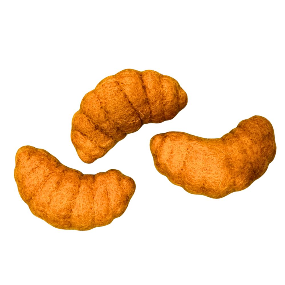 Set of three croissant-shaped cat toys  made of wool shown together, each with curved pastry shape and textured felt surface for batting and play.