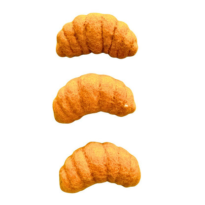 Three croissant-shaped wool cat toys stacked vertically on a white background, each showing a curved pastry shape and textured felt surface designed for interactive cat play