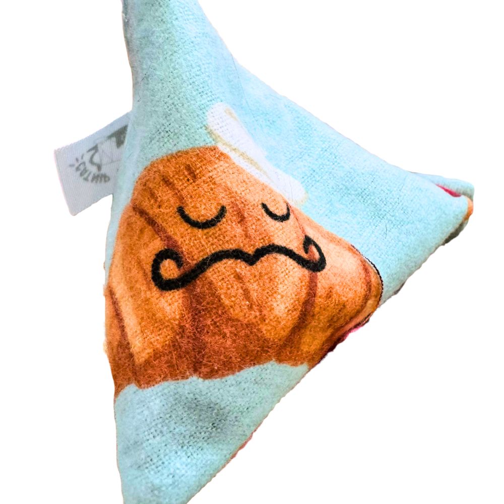 CatnipTakeout Croissant Happy Sack cat toy featuring a cream bakery print fabric with croissants, pastries, and dessert illustrations on a pyramid shape, stitched for durability and filled with catnip to encourage interactive batting and pouncing