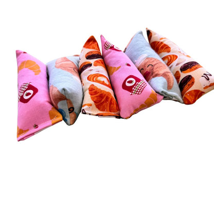 CatnipTakeout Croissant Mini Kicker Catnip Toy featuring slim, elongated mini kicker shapes designed for kittens and adult cats. Shown in bakery-themed cotton fabrics including pink croissant and jam print, light blue croissant character print, and cream pastry print with croissants and desserts. Sized for easy grabbing, bunny kicks, and self-directed play, filled with CatnipTakeout’s signature aromatic catnip.