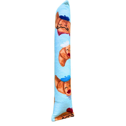 CatnipTakeout Croissant Kicker Catnip Toy featuring a full-length kicker shape designed for bunny kicks, gripping, and wrestling. This version shows a playful croissant character print on a soft blue background with whimsical facial expressions, giving strong visual contrast cats love. Long and slim profile supports interactive play for kittens and adult cats, while the kicker is filled with CatnipTakeout’s signature aromatic catnip for extended engagement and enrichment.