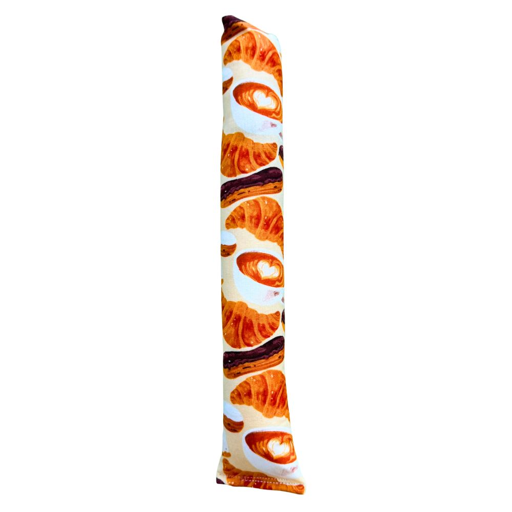 CatnipTakeout Croissant Kicker Catnip Toy shown as a full-length kicker designed for grabbing, wrestling, and bunny-kicking. Features a café-style croissant pastry fabric with repeating illustrated croissants, espresso drinks, and bakery treats in warm golden browns and creamy neutrals. Long, sturdy kicker shape supports interactive play and energetic solo sessions, and is filled with CatnipTakeout’s signature aromatic catnip to keep cats engaged longer.