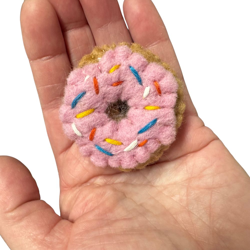 Pink wool Donut Cat Toy with catnip shown in hand for size reference, ideal batting toy for bored indoor cat
