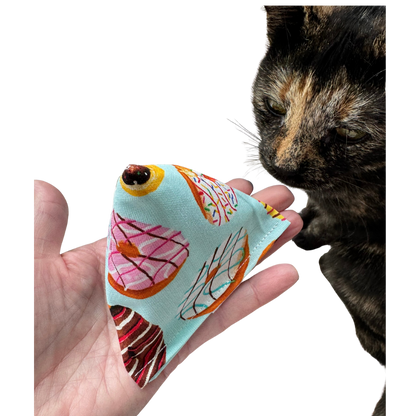 Donut cat toy Happy Sack shown in hand beside a tortoiseshell cat for size and cat-approved play