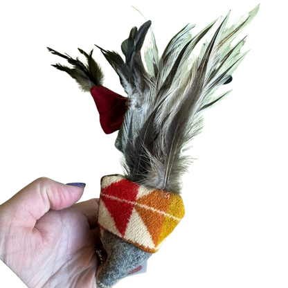 Hand holding a cat toy with feathers and geometric pattern on a white background