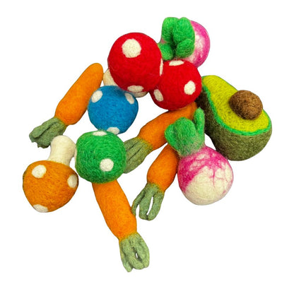 Flat lay of assorted veggie cat toys featuring multiple carrots, red and blue polka-dot mushrooms, a green avocado half, and a pink-and-white radish arranged together on a white background. Made by CatnipTakeout