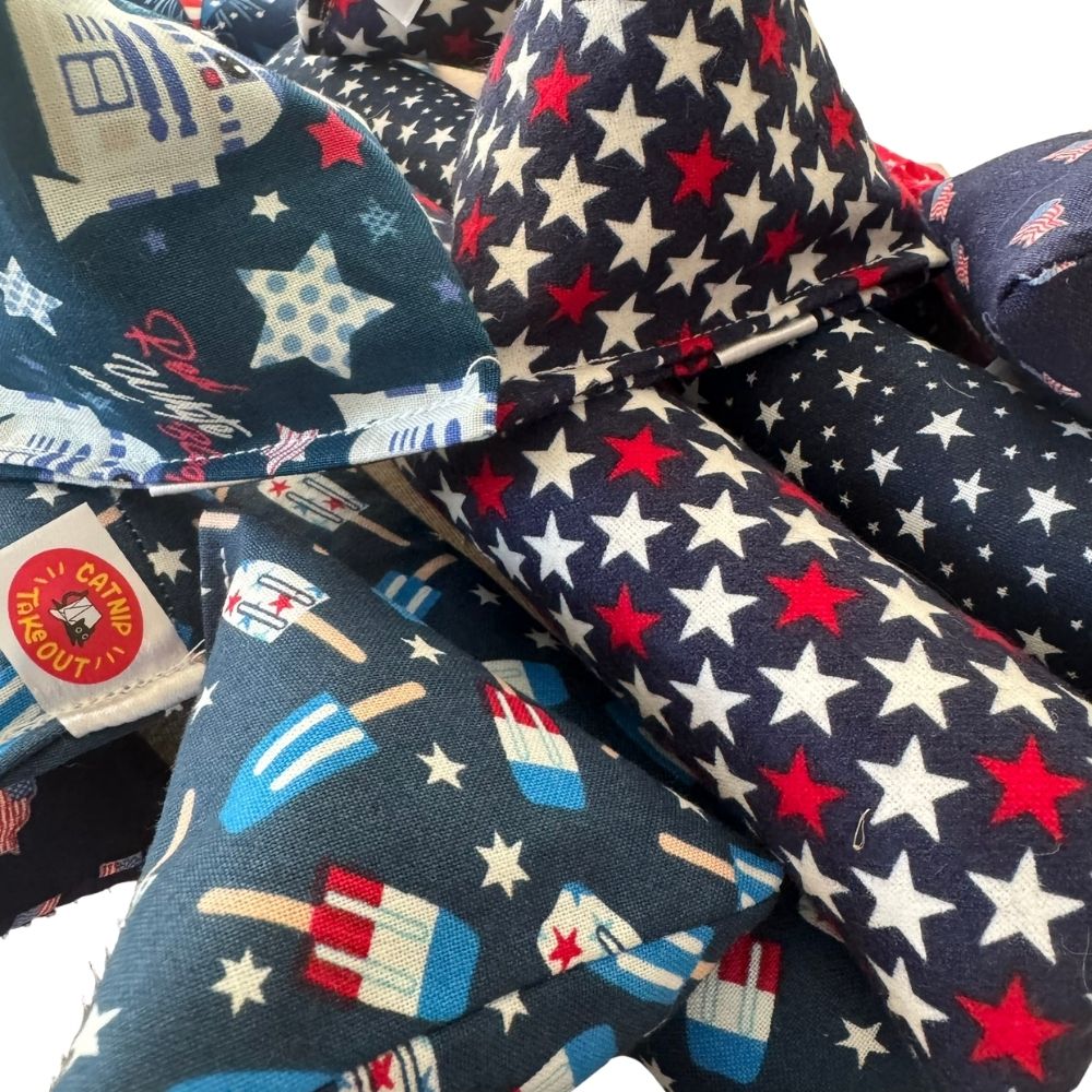 Close view of patriotic Happy Sack, Mini Kicker, and Kicker catnip toys featuring stars, popsicles, and festive summer prints