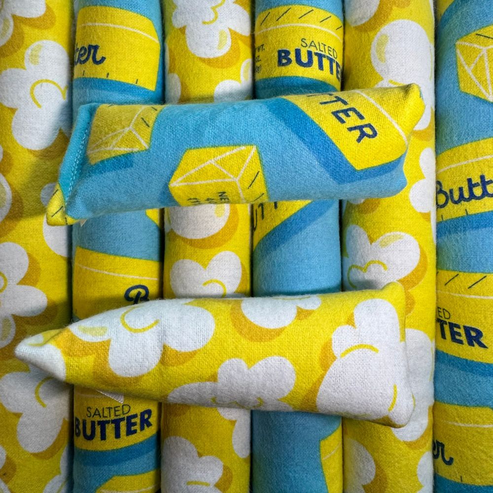 Stacked catnip kicker and mini kicker cat toys showing both popcorn print and butter print fabrics arranged vertically
