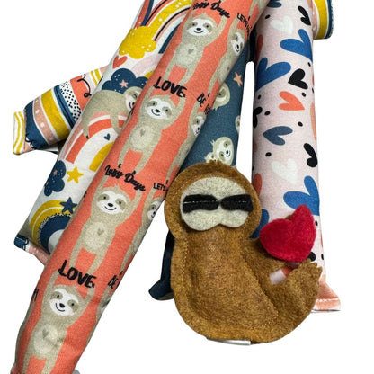 Handmade sloth kicker and Happy Sack cat toys shown together in five Valentine sloth prints, filled with signature premium catnip and designed for kicking, pouncing, and cozy play. Made by CatnipTakeout.