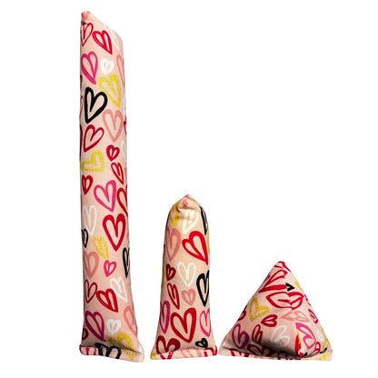 Group photo of three handmade Valentine scribble hearts cat toys: one long Kicker, one Mini Kicker, and one pyramid Happy Sack in a multicolor hearts pattern, filled with signature premium catnip. Made by CatnipTakeout.