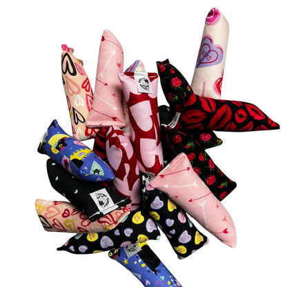 Group photo of handmade Valentine cat toys including kickers and Happy Sacks together, featuring arrows, hearts, roses, candy hearts, playful cats, and lip designs, all filled with signature premium catnip. Made by CatnipTakeout.
