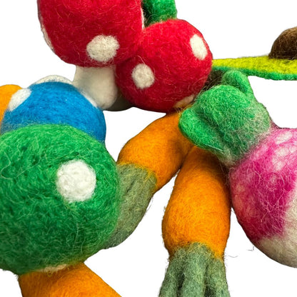 Close-up detail of veggie cat toys highlighting felted textures, including green and blue polka-dot mushrooms, carrot tops, and a pink-and-white radish. Shows dense fibers and handcrafted detailing. Made by CatnipTakeout